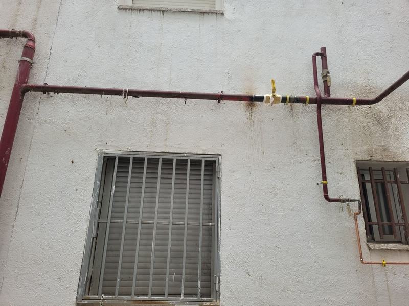 Montante de gas con llave de corte y tubería vista instalada en fachada